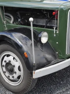 Front part of a vintage car with visible wheel and mechanical details