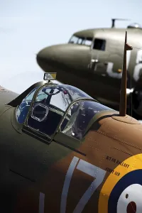 A vintage Spitfire fighter plane pictured in front of a DC-3 transport aircraft from World War Two at the Cotswold