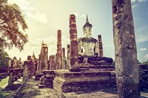Vintage style buddha statue sitting in the ruins under the bright sky of Wat Maha That temple at Sukhothai Historical