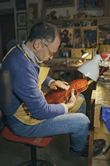 Violin maker carefully crafting a new instrument in his workshop surrounded by various tools showcasing his skills