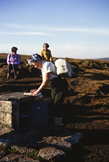 Visitor signing the guestbook, letterbox at Cranmere Pool, Dartmoor National Park, Devon, England, UK 1975
