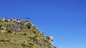 Visitors gather on a rocky viewpoint and watch birds in the clear sky
