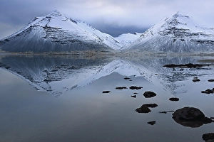 Volcanic mountains in winter with reflection in the water