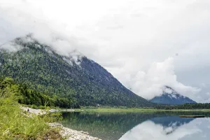 Vorderriss, Bavaria, Germany, A tranquil lake reflects forested mountains and clouds