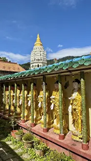 Walking tour with Buddhist statues and a pagoda visible in the background under a clear blue sky