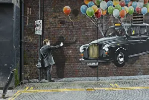 Wall graffiti, man hailing a taxi hanging on flying balloons