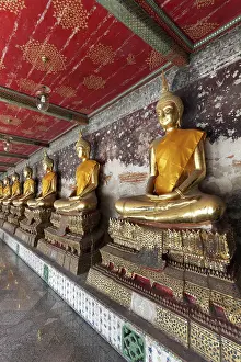 Wall with row of golden Buddha statues in meditation posture