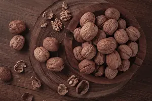 Walnuts are gathered and placed in a wooden bowl on a wooden table