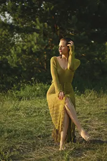 On a warm day, a woman sits gracefully by the lake surrounded by lush greenery