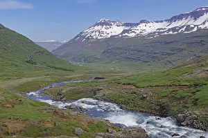 Water falls into a deeply incised valley framed by high mountains