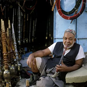 A water pipe seller smokes a water pipe in the souk in the old town of Sanaa, UNESCO World Heritage Site, Sanaa, Yemen, Asia