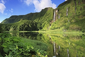 Waterfalls on the forested slope of a volcano reflected in a lake