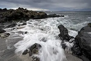 Waves blaze on the beach, rocky coast with volcanic stones