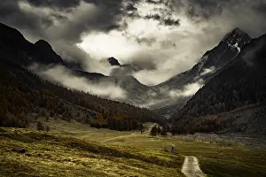 Way cross with path in autumnal mountain landscape with threatening cloudy sky