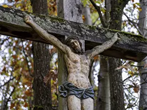 Weathered crucifix with lichen on a wooden cross on a forest path in the Rhon