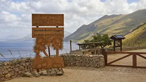 Welcome sign, stone wall, green mountains