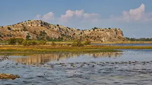 Wetland with a view of rocky hills and scattered clouds in the sky