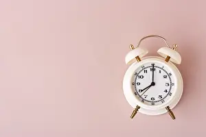 White alarm clock on pink background place text