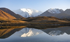 White glaciated and snowy mountain peak Pik Lenin at sunset