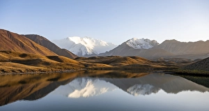 White glaciated and snowy mountain peak Pik Lenin at sunset