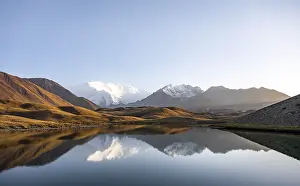 White glaciated and snowy mountain peak Pik Lenin at sunset