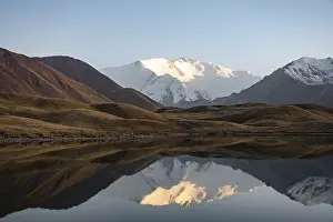 White glaciated and snowy mountain peak Pik Lenin at sunset