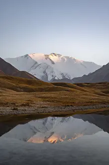 White glaciated and snowy mountain peak Pik Lenin at sunset