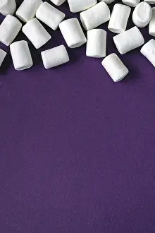 White marshmallow scattered over purple background
