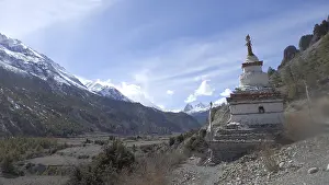 White stupa in front of a majestic mountain landscape with clear skies