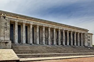 A wide building with many columns and large stairs in front of a slightly cloudy sky