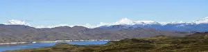 Wide landscape view of snowy mountains and lake under a clear sky