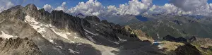 A wide panoramic shot capturing the rugged mountain range with patches of snow and rocky terrain