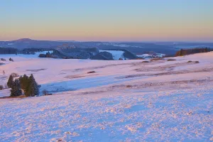 Wide snow-covered landscape with gentle hills in the morning light
