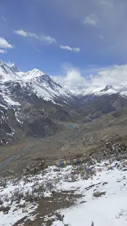 Wide valley with prayer flags and snow-capped mountains in the background under clear skies