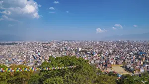 Wide view of a big city, colorful prayer flags in the foreground
