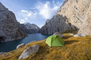 Wild camping, camping in the wilderness with a tent in front of mountain lake Kol Suu