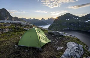 Wild camping with tent, sun shining over mountain landscape with fjord and lake Krokvatnet