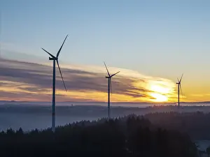 Three wind turbines in front of a foggy