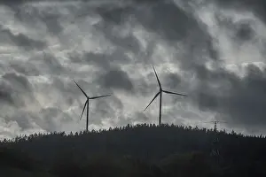 Wind turbines in pine forest during thunderstorm