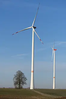 Two wind turbines tower high in the sky on a wide green field
