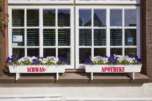 Window with flower boxes of the Swan pharmacy in the city centre of Husum