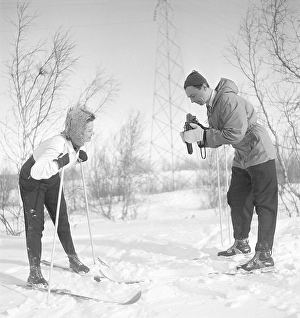 Winter in the 1940s. Actor Nils Kihlberg, 1915-1965 is pictured here with his wife Ann-Britt. He is taking pictures of her on their winter vacation. They are both wearing winter clothes and skis. The camera is a Rolleiflex by german company Rollei