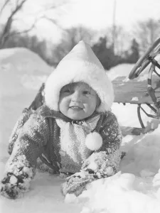 Winter in the 1940s. A child has fallen from the sledge but doesn't seem to mind
