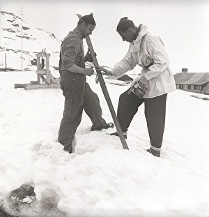Winter in the 1940s. Two men are going skiing and prepares the skis with ski wax to get better traction on the snow