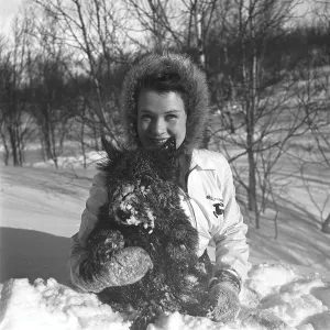 Winter in the 1940s. A young woman in the snow with her dog