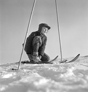 Winter in the 1950s. A boy is seen putting on his skis on a sunny winter day 1950