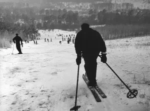 Winter sports, man drives down the slope and looks into a valley full of skiers