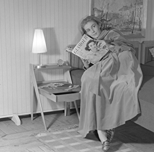 Woman of the 1950s. A young woman in the bedroom is lying comfortably reading the magazine Glamour