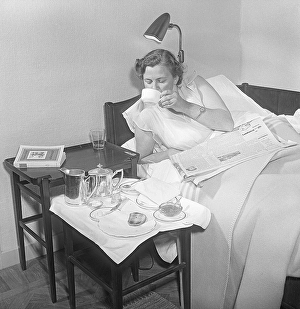 Woman of the 1950s. A young woman is lying in bed and serviced with a breakfast meal