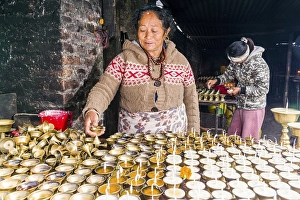 Category Buddhism Prints: A woman is arranging butter lamps at a temple in Boudha